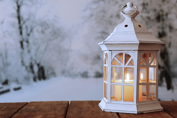 Lantern on wooden table on winter background