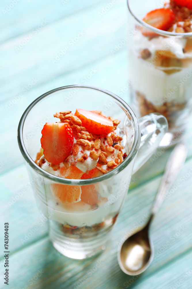 Healthy layered dessert with muesli and strawberries on table