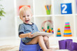 child sitting on chamber pot playing tablet pc