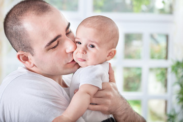 Gentle young father comforting crying baby