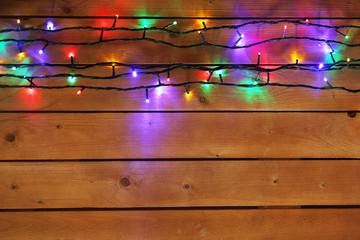 Wall Mural - Christmas lights garland on wooden background