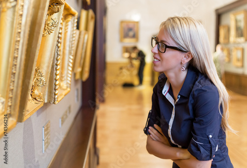 Fotografie, Obraz Woman looking at old paintings in art gallery