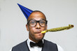 Young geek celebrating with party blower and hat