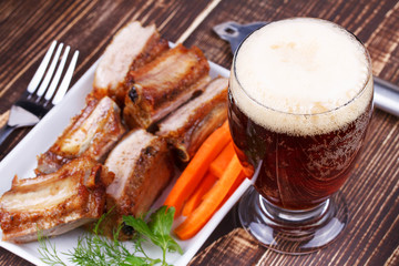 Wall Mural - Glass of beer, grilled pork ribs and carrot on wooden background