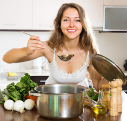 Woman cooking soup in kitchen