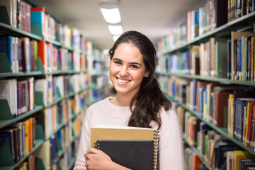 In the library - pretty female student with books working in a h