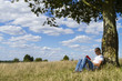 © icsnaps - Man reading a book under the shade of a tree