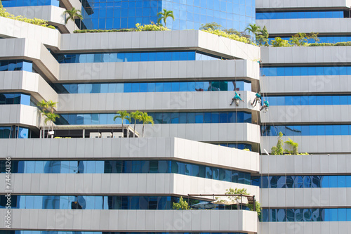 Fotografie, Obraz Man cleaning windows on a high rise building