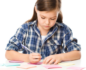 Wall Mural - Girl is writing on color stickers using pen