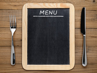 fork, knife and blackboard menu on wooden background