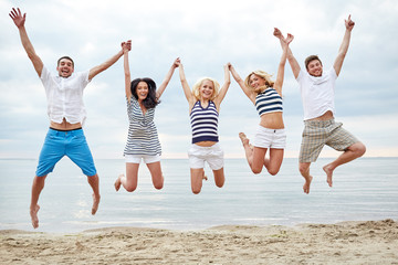 Wall Mural - smiling friends in sunglasses walking on beach