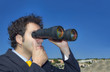 Business man  with binoculars looking at the sky
