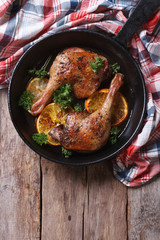 Canvas Print - Fried duck leg with oranges in a pan vertical top view