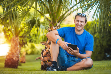 man with tablet in the palm garden