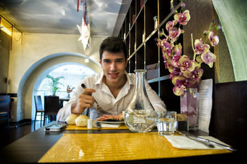 Handsome young man having lunch in elegant restaurant