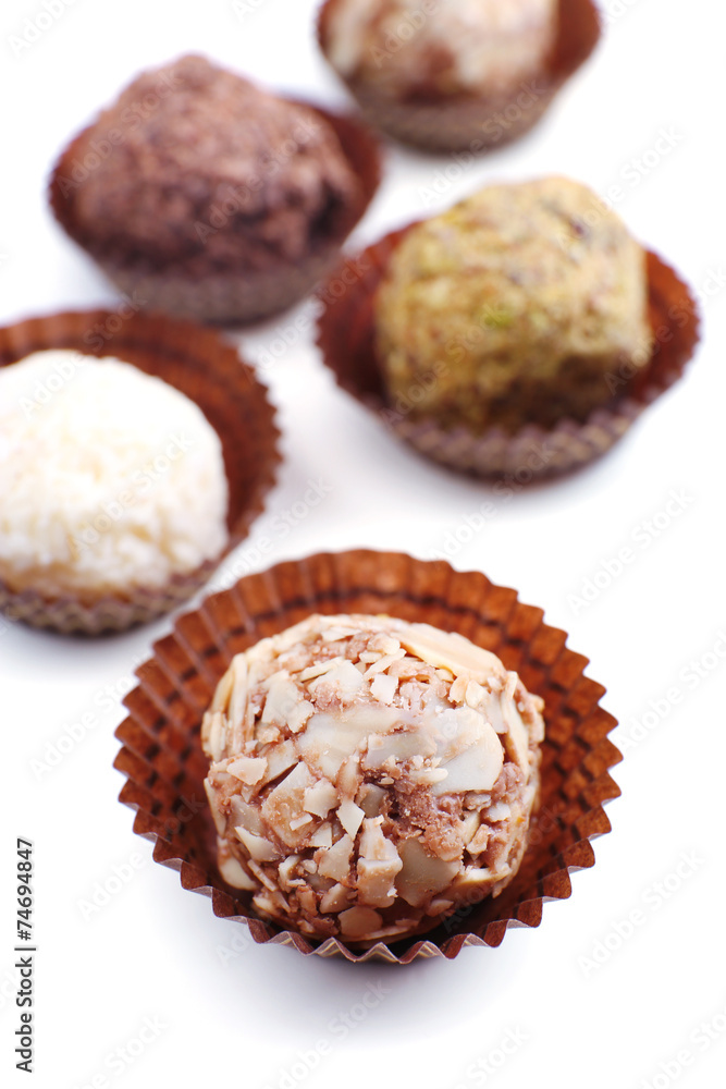 Sweet round candy wrapped in paper bowl on white background