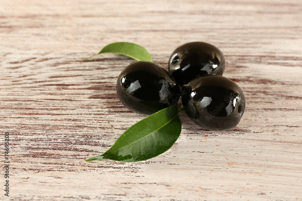 Tree black olives with leaf on painted wooden background