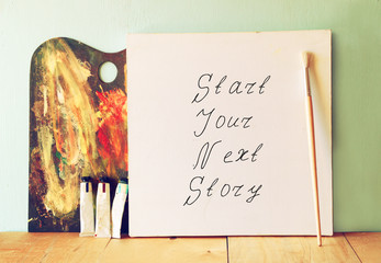 Wall Mural - canvas with the phrase start your next story next to oil paints 