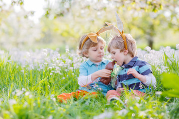 Two children wearing Easter bunny ears and eating chocolate