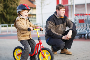 Wall Mural - Little toddler boy with bicycle and his father in the city