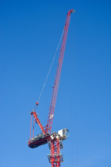 Red construction crane on clear blue sky