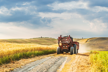 Wall Mural - Tractor with a trailer on the fields in Tuscany, Italy