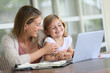 © goodluz - Little girl looking at laptop computer with her mom