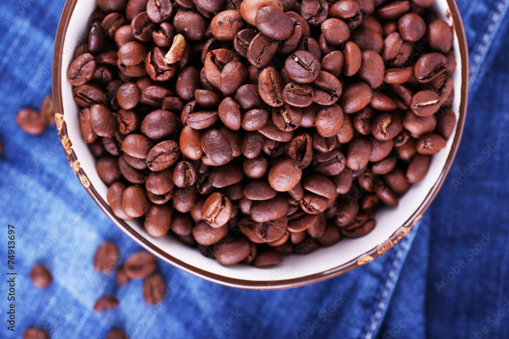 bowl of coffee beans stands on jeans background