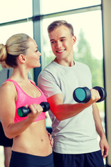 Canvas Print - smiling young woman with personal trainer in gym