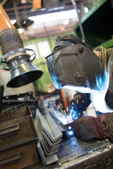 Industrial worker welder welding metal at factory workshop