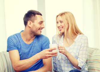 Canvas Print - smiling man giving cup of tea or coffee to wife