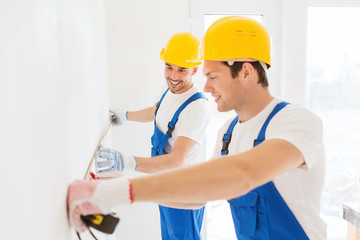 Canvas Print - smiling builders with measuring tape indoors