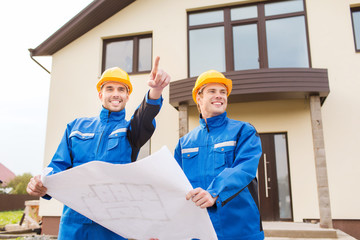 Poster - smiling builders with blueprint pointing finger