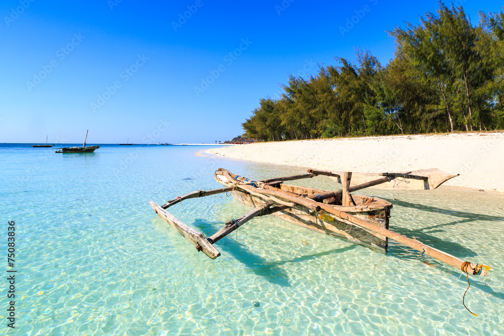 Traditional fisherman boat lying near the beach in clear water - obrazy, fototapety, plakaty 