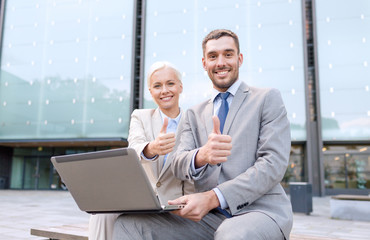 Canvas Print - smiling businesspeople with laptop outdoors