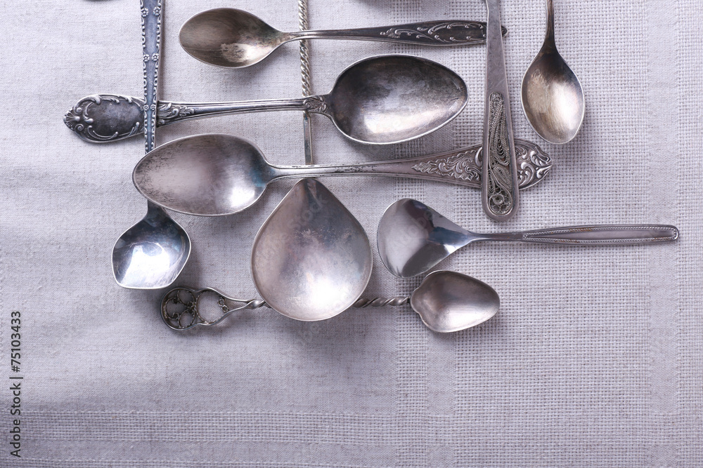 Metal spoons on fabric background