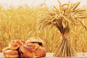 bread and wheat on the wooden table in autumn field