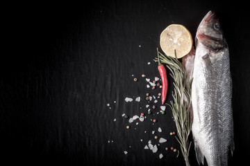 Wall Mural - Fresh fish, lemon, pepper and rosemary on a black background. Ti