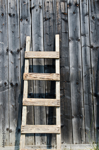 Obraz w ramie Old wood ladder leaning over a grey wooden wall.