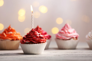 Wall Mural - Delicious birthday cupcakes on table on light background