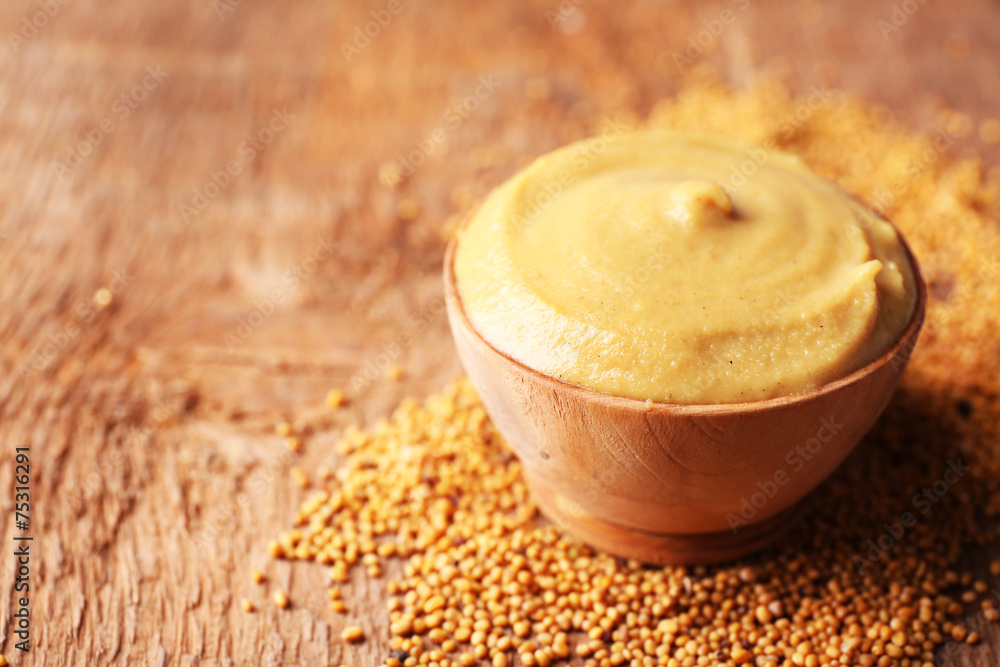 Mustard in bowl on wooden background