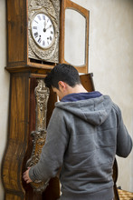 Young Man Winding The Mechanism On A Clock