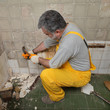 © sima - Home renovation, worker demolish tiles in a bathroom