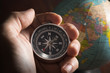 © peerayot - Compass in human hand with globe.