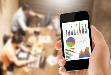 hand holding mobile phone with analyzing graph