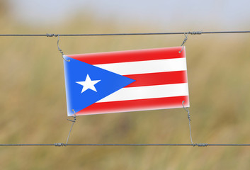 Wall Mural - Border fence - Old plastic sign with a flag