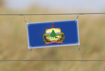 Wall Mural - Border fence - Old plastic sign with a flag