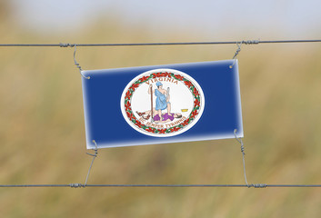 Wall Mural - Border fence - Old plastic sign with a flag