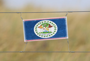 Wall Mural - Border fence - Old plastic sign with a flag