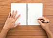 Man hand writing notebook on wood background